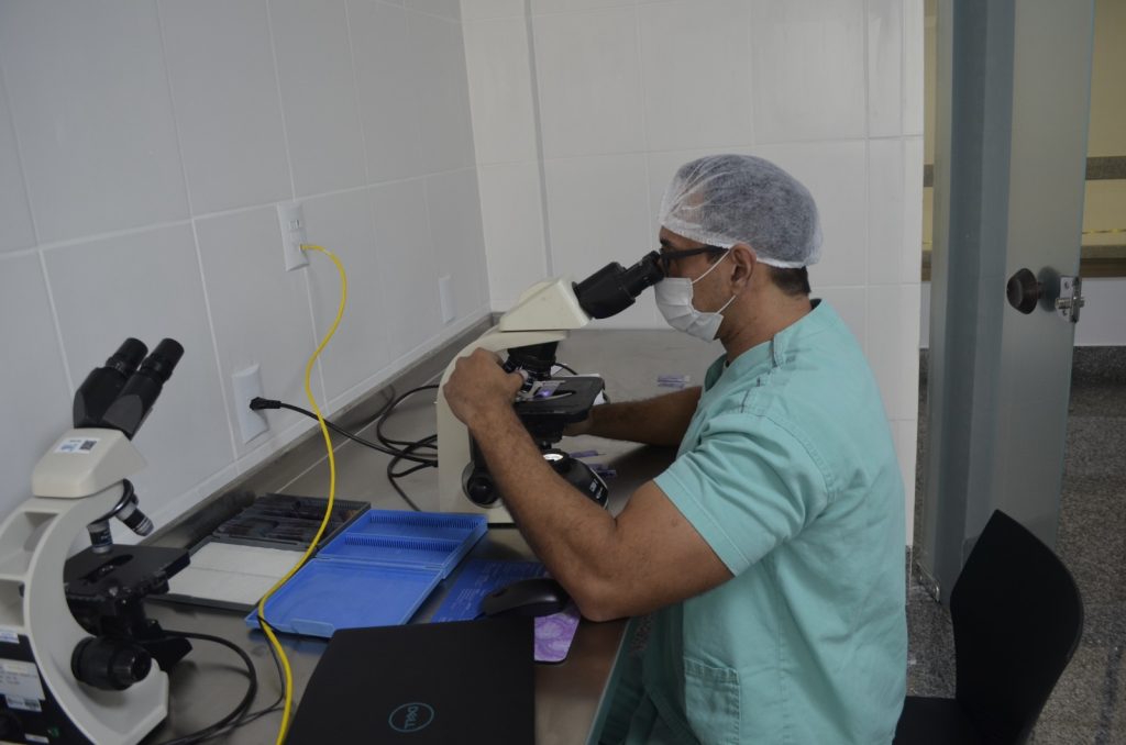 Médico patologista do hospital realizando o procedimento de biópsia por congelação no microscópio