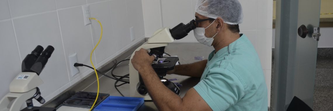 Médico patologista do hospital realizando o procedimento de biópsia por congelação no microscópio